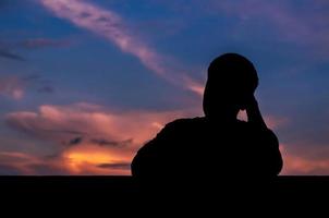 Silhouette of asian man stay alone with dusk sky background. Depression and mental health concept. photo