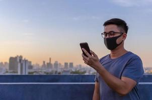 Partial focus of asian man wearing face mask to protect from dust and pollution while make a video call with smartphone. photo