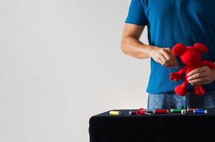 hombre en un papel no estereotipado haciendo tareas domésticas cosiendo la muñeca para niños sobre fondo blanco. foto