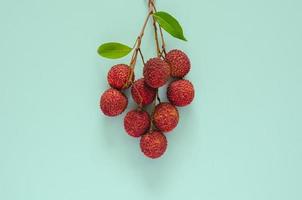 Fresh lychee fruits with leaves on blue color background. Top view background concept. photo