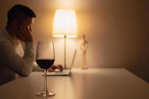 una copa de vino tinto se pone sobre la mesa para beber y relajarse cuando se trabaja en casa. foto