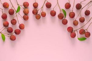 frutas frescas de lichi con tallo y hojas, frutas asiáticas exóticas sobre fondo rosa. foto