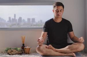Asian man practicing meditation at home photo