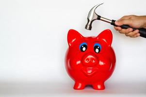 Red piggy bank with hand holding the hammer puts on white background photo