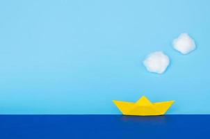 Yellow paper boat moving on blue sea. photo