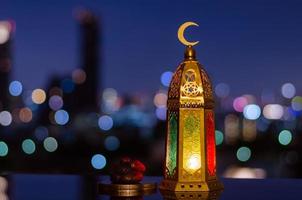 Lantern that have moon symbol on top and small plate of dates fruit photo