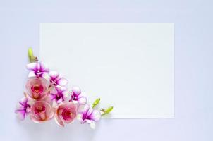 Empty white paper for text with orchids flower on pastel purple background.