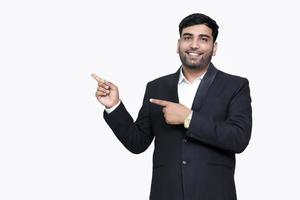 Portrait of a happy businessman pointing finger away over white background. photo