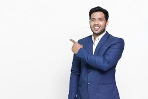 Portrait of a happy businessman pointing finger away over white background. photo