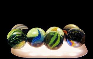 Close-up shot of glass marbles with light underneath. Diversity of the color of marbles photo
