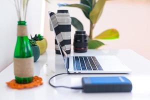 lugar de trabajo del fotógrafo, computadora portátil y lentes de cámara en una mesa blanca foto