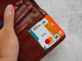sidoarjo, jawa timur, indonesia, 2022 - tarjetas de cajero automático de varios bancos en el bolsillo de la cartera de mano de los hombres foto