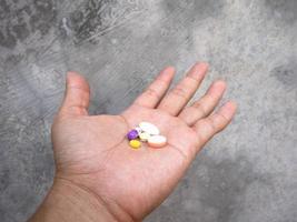 a man puts supplement medicine in the palm of his hand photo