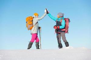 dos mujeres caminan con raquetas de nieve en la nieve, chocan los cinco foto