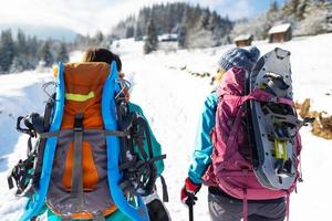 Two women walk with snowshoes on the backpacks, winter trekking photo