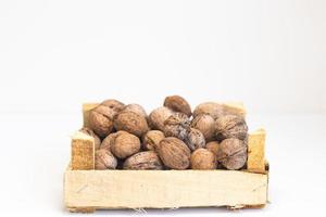 Wooden container with walnuts on a white table photo