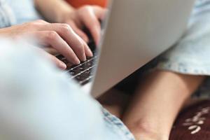 manos femeninas en el teclado, la chica trabaja en una laptop y escribe foto