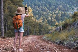 A girl photographs a beautiful mountain landscape on a smartphone photo