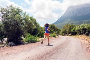 A girl runs along a mountain trail photo