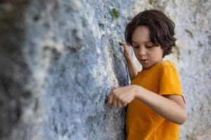 A little rock climber is training to climb a boulder photo