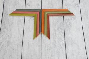 Simple wooden samples of colored picture frames stacked in an angle in a row close-up on a gray background. Colored corners for a baguette. photo