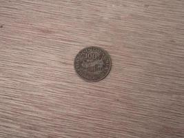 foto de primer plano de la moneda indonesia de 100 rupias sobre un fondo de tablón de madera marrón