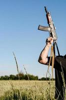 un soldado con rifles de asalto militares de combate ak 74 se encuentra en un campo, campos de trigo ucranianos y guerra. foto