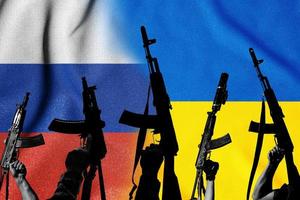 Two enemy flags and combat military assault rifles AK 74 and AK 74U on their background. photo