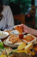 A young woman is happy to see the food on the table and choose the pizza menu to eat with good taste. Pizza menus are perfect for banquets among friends and family as they are comfortable to eat photo