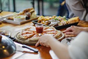 A young woman is happy to see the food on the table and choose the pizza menu to eat with good taste. Pizza menus are perfect for banquets among friends and family as they are comfortable to eat photo