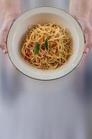 Spaghetti stir-fried with tomato sauce and minced chicken in hot Thai style. Tender and delicious served in a white plate placed on a wooden table, resulting in a delicious spaghetti from the sauce. photo
