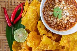 albóndigas crujientes envueltas en pollo, verduras y especias se sirven en un plato blanco colocado sobre una mesa de madera dentro del restaurante. Las albóndigas fritas son populares por su delicioso sabor. foto