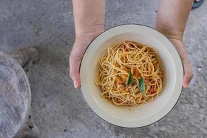 Spaghetti stir-fried with tomato sauce and minced chicken in hot Thai style. Tender and delicious served in a white plate placed on a wooden table, resulting in a delicious spaghetti from the sauce. photo