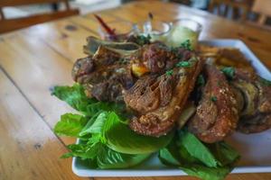 German pork knuckle is served with baked potatoes and sauce inside a white ceramic plate placed on the dining room table to make the pork knuckle ready for a dinner feast. photo