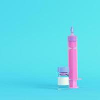 Pink syringe with vaccine on bright blue background in pastel colors photo