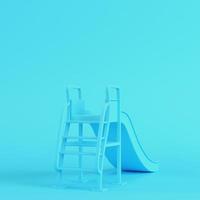 Children slide on bright blue background in pastel colors photo