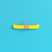 Yellow canoe with paddles on bright blue background in pastel colors photo