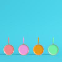 Four colorful frying pans on bright blue background in pastel colors. photo