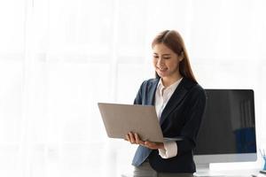 Portrait of a happy asian businesswoman working on laptop computer with copy space. photo