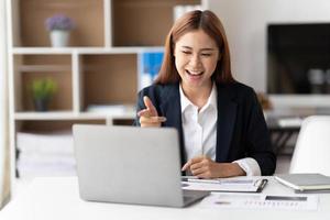Young attractive business asian woman talking about sale report in video call conference on notebook computer online meeting in working from home. photo