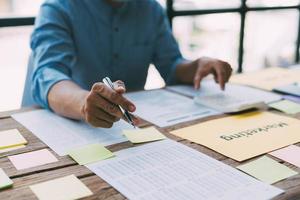 El personal financiero masculino asiático está explicando el desempeño del gráfico de barras de rápido crecimiento de la compañía este año. a su jefe en el escritorio de la oficina, concepto de finanzas foto