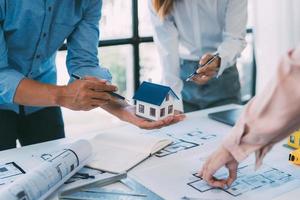 A group of architects are designing a house model, engineers and architects working together to plan a house building project. photo