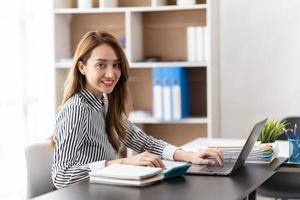 Portrait of Young Asian businesswoman is happy to work at the modern office using a laptop computer. business employee freelance online marketing e-commerce telemarketing concept. photo