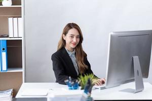 el retrato de una joven empresaria asiática está feliz de trabajar en la oficina moderna usando una computadora portátil. concepto de telemarketing de comercio electrónico de marketing en línea independiente para empleados de negocios. foto