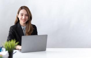 el retrato de una joven empresaria asiática está feliz de trabajar en la oficina moderna usando una computadora portátil. concepto de telemarketing de comercio electrónico de marketing en línea independiente para empleados de negocios. foto