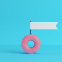 Donut with blank flag on bright blue background in pastel colors photo