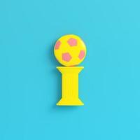 Yellow column with soccer ball on bright blue background in pastel colors photo