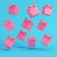 Pink flying gift boxes with ribbon bow and christmas ball on bright blue background in pastel colors