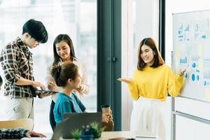 group of four happy young asian corporate people teammates meeting discussing business in office. photo