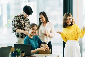 group of four happy young asian corporate people teammates meeting discussing business in office. photo